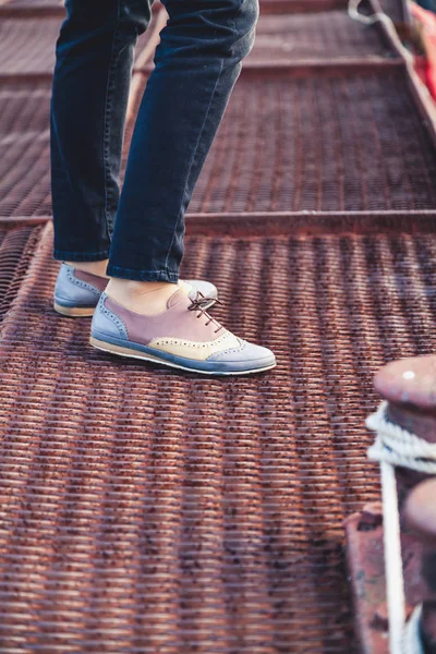 Female feet in the pants and shoes on the dock — Stock Photo, Image