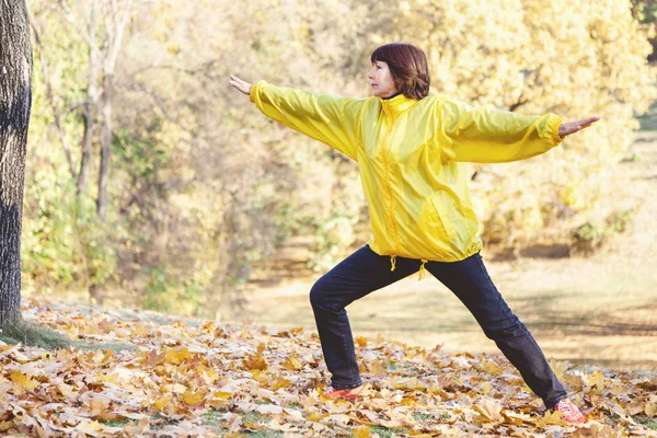 Olgun güzel kadın sonbahar orman jimnastik yapan