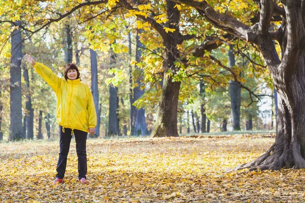 Beautiful elderly woman doing exercises in the autumn forest — Stock Photo, Image