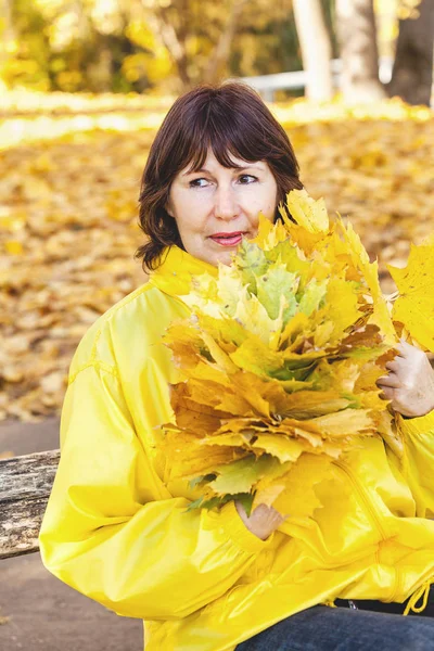 Belle femme plus âgée tenant des feuilles d'érable tombées — Photo