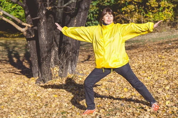 Reife hübsche Frau auf einer Waldlichtung zu üben — Stockfoto