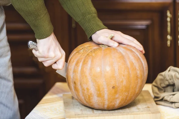 Hands of man cut ripe pumpkin with big knife — Stock Photo, Image