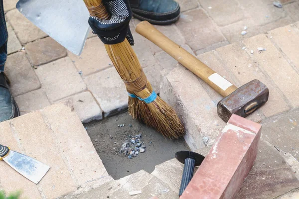 Garbage collection. Broom collects debris between bricks — Stock Photo, Image