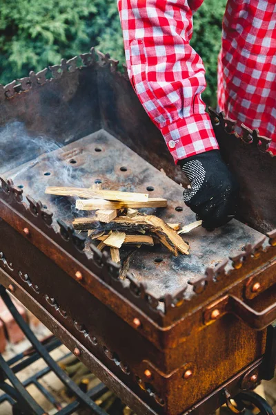 Рука кладет крошечные чипсы в огонь жаровни близко — стоковое фото