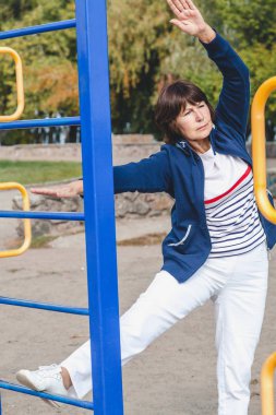 yaşlı kadın gerçekleştirir yaz çömelme spor zemin