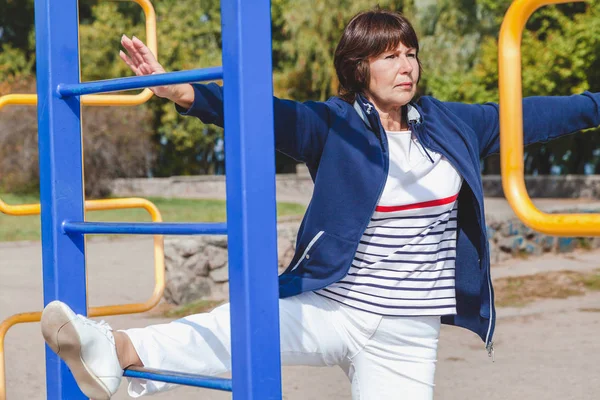 yaşlı kadın gerçekleştirir yaz çömelme spor zemin