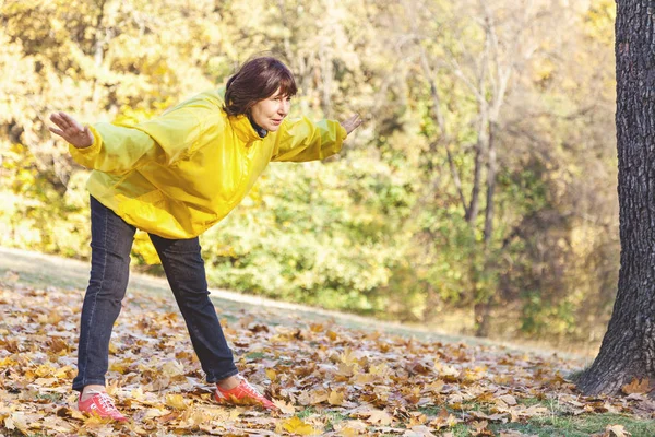 Mature pretty woman to exercise in a forest glade — Stock Photo, Image