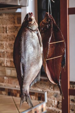 İki büyük füme balık tuğla duvar arka plan üzerinde asılı