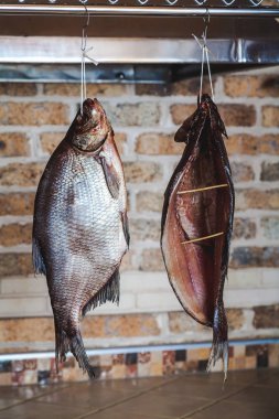 İki büyük füme balık tuğla duvar arka plan üzerinde asılı