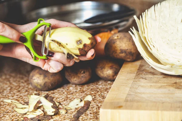 Чистить картошку. Женские руки чистый картофель специальный инструмент — стоковое фото