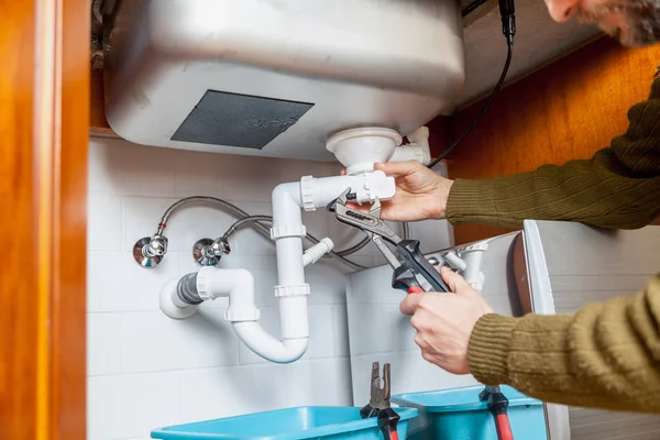 Repair of kitchen overflow pipe wrench closeup — Stock Photo, Image