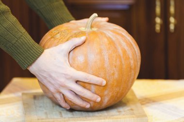 Adam olgun kabak kesme tahtası üzerinde tutan eller