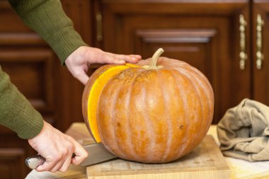 Eller erkek olgun kabak parçası büyük bıçak ile kesmek.