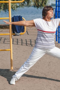 Jimnastik sahilde. emekli kadın egzersizleri kumlu g üzerinde gerçekleştirir.