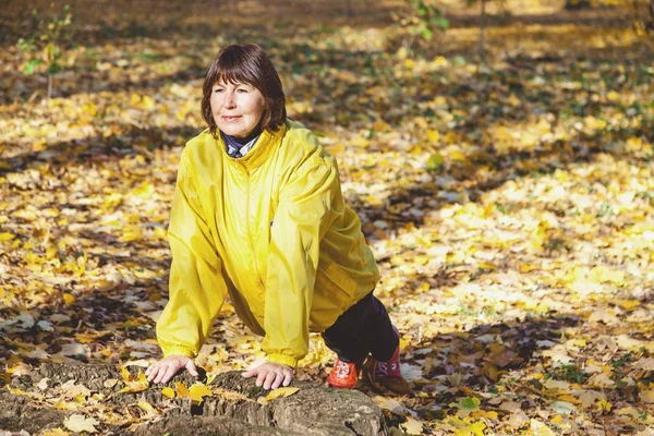 Активная пожилая женщина делает гимнастические упражнения на лесной поляне — стоковое фото