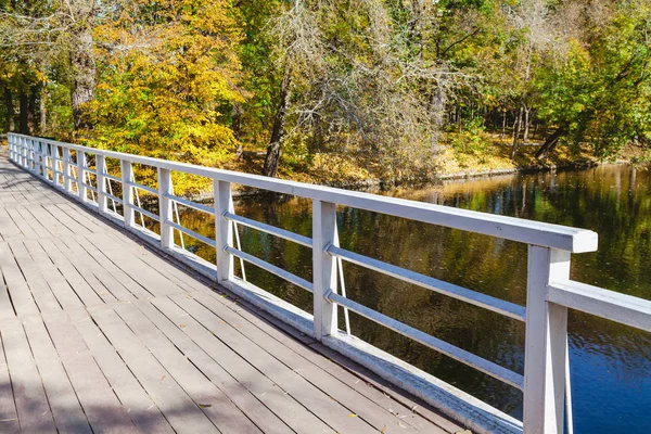 Wooden footbridge over the river a bright autumn day