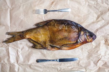 Büyük füme balık, bıçak ve çatal parşömen kağıt üzerinde.