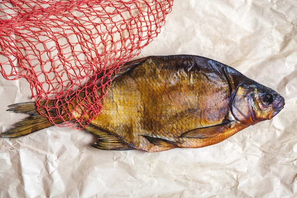 La plupart des poissons fumés sur du papier parchemin à côté de la grille rouge — Photo