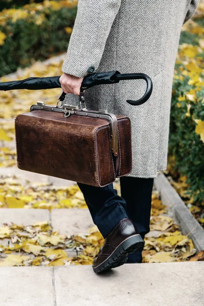 Человек с сумкой и в пальто прогулки по осенней улице — стоковое фото