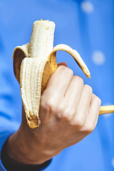 Mão de homem segurando banana mordida — Fotografia de Stock