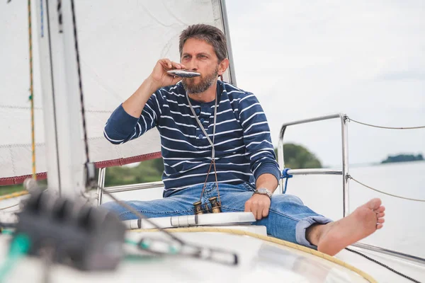 Чоловік сидить на вітрильній яхті і п'є — стокове фото