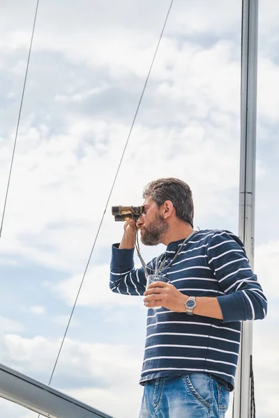 Человек с бородой пьет виски на яхте — стоковое фото