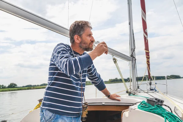 Hombre con barba bebe whisky en yate — Foto de Stock