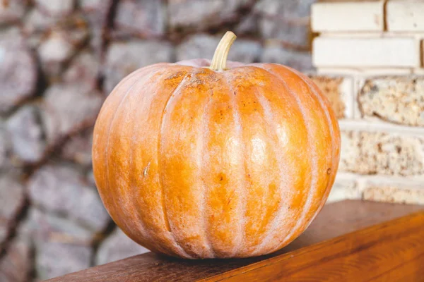 Large orange pumpkin lies on wooden railing of veranda — Stock Photo, Image