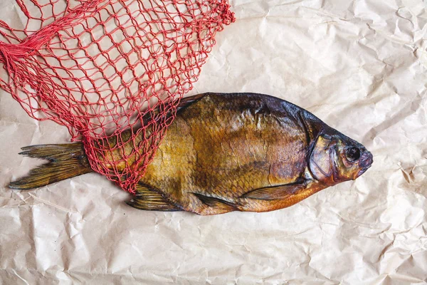 La plupart des poissons fumés sur du papier parchemin à côté de la grille rouge — Photo