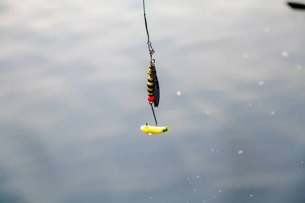 Colher de fiação amarela acima da superfície da água — Fotografia de Stock