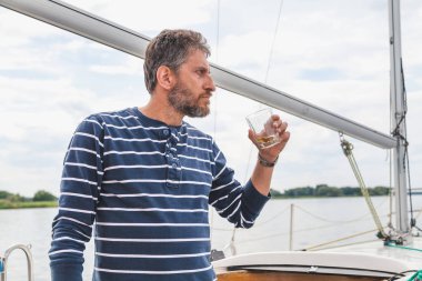 sakallı adam viski yatta içecekler.