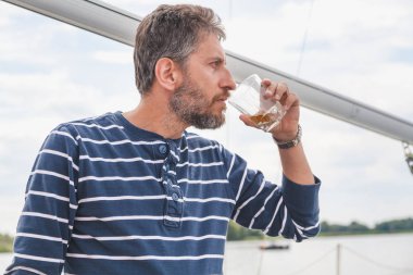 sakallı adam viski yatta içecekler.