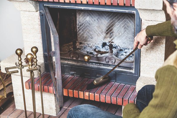 man cleans fireplace with brush and blades