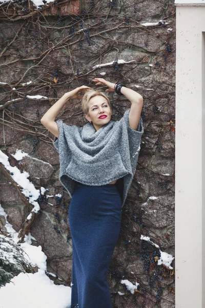 Carino donna in maglione grigio sta contro muro di pietra — Foto Stock