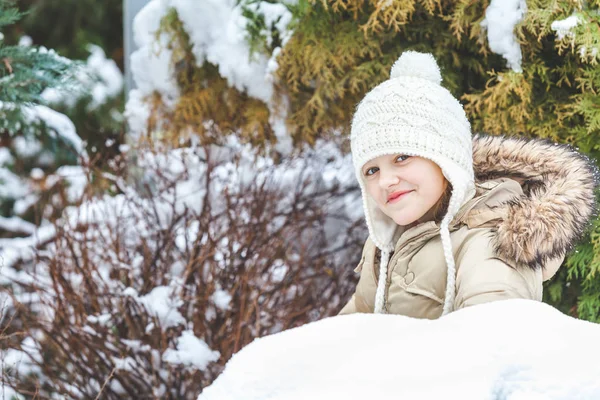 Niña en chaqueta encapuchada acostada en la nieve —  Fotos de Stock