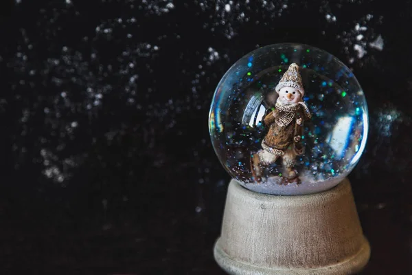 Bola de vidro com neve e floco de neve no fundo escuro — Fotografia de Stock