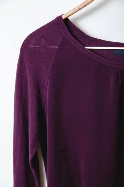 Фиолетовый свитер весит на деревянной вешалке — стоковое фото
