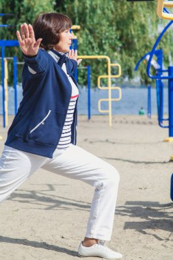 yaşlı kadın gerçekleştirir yaz çömelme spor zemin