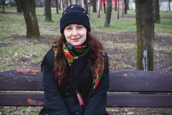 Красивая молодая женщина в русском шарфе сидит на скамейке — стоковое фото
