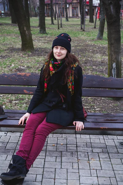 Bella giovane donna in sciarpa russa seduta su panchina — Foto Stock
