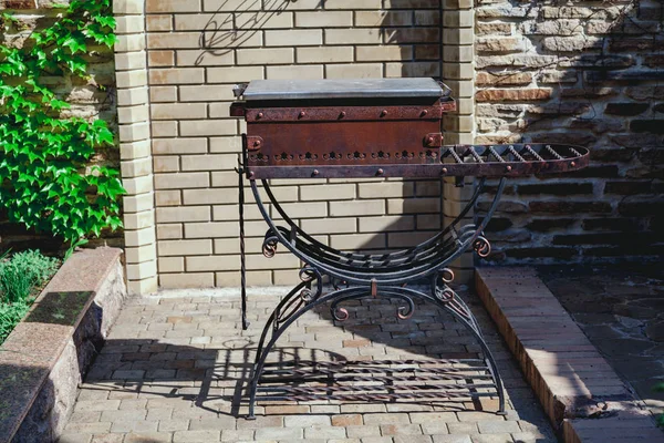 Elegant forged brazier stands in yard on summer day — Stock Photo, Image