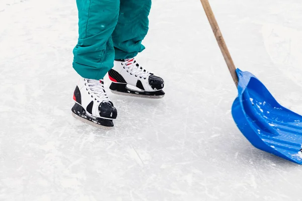 Homme sur patins nettoie une pelle de glace sur patinoire — Photo