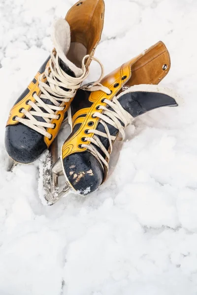 Paar gele lederen schoenen met schaatsen liggen op sneeuw — Stockfoto