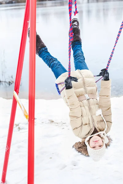 Chica joven montando swing al revés en estanque de invierno —  Fotos de Stock
