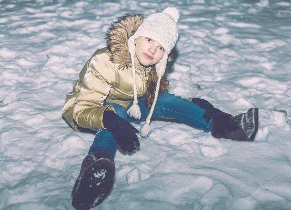 Young girl in yellow jacket sitting in snow — Stock Photo, Image