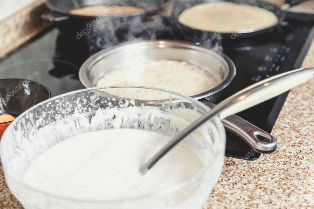 cooking pancakes in several pans
