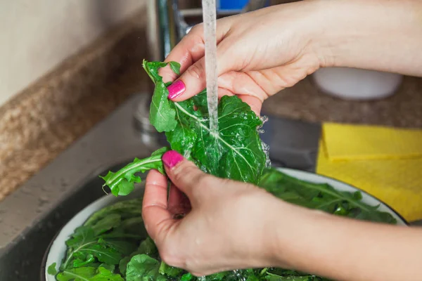 Hands of woman washing green leaves of arugula — Stock Photo, Image