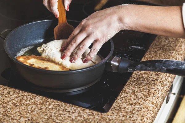 Женская рука на кастрюле с пирогом на электрической плите — стоковое фото