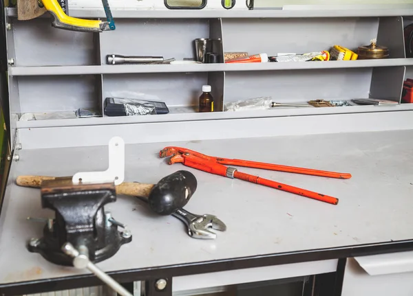 Weiße Ecke in Schraubstock eingeklemmt. Dahinter liegen Hammer und Schraubenschlüssel — Stockfoto