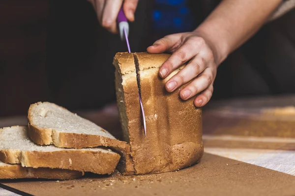 woman hands slice fresh bread slices with knife.